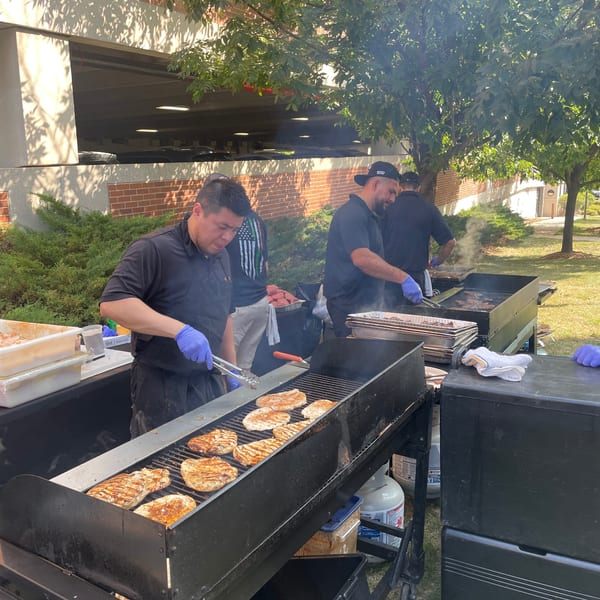 Chefs grilling chicken and other meats on large outdoor grills at Bailey's Smokehouse.