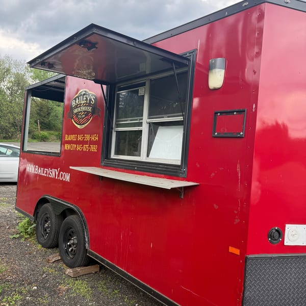 Red Bailey's Smokehouse food truck with open serving windows and logo on the side.