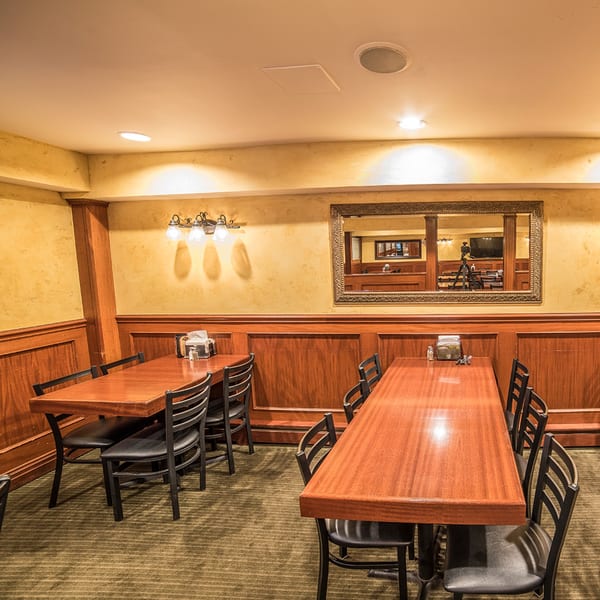 Dining room at Bailey's Smokehouse with wooden tables, black chairs, and a large mirror.