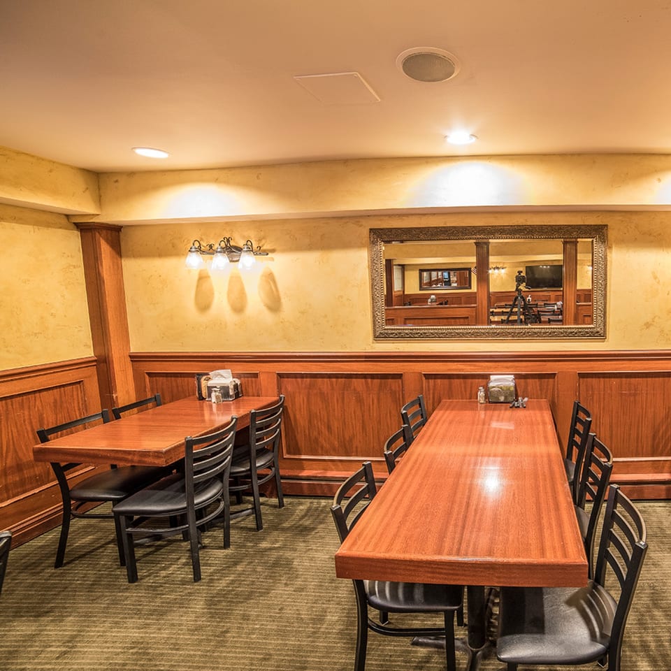 Dining room at Bailey's Smokehouse with wooden tables, black chairs, and a large mirror.