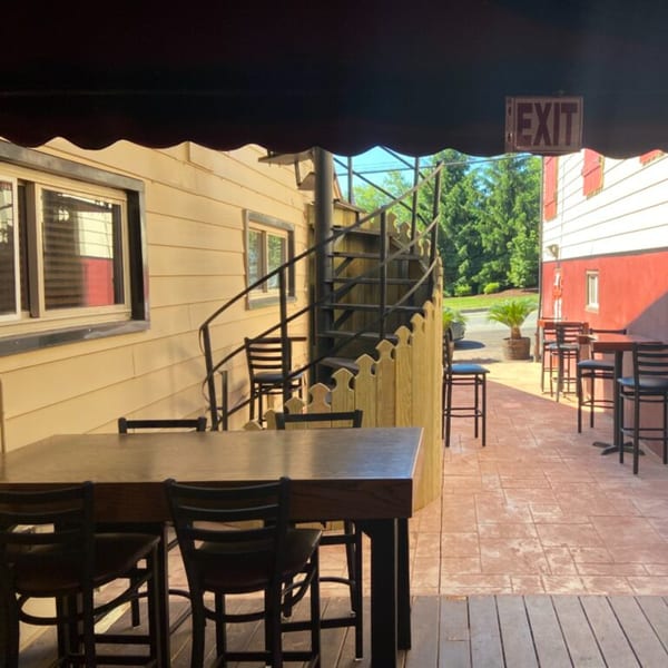 Outdoor patio seating at Bailey's Smokehouse with high-top tables, chairs, and a spiral staircase.