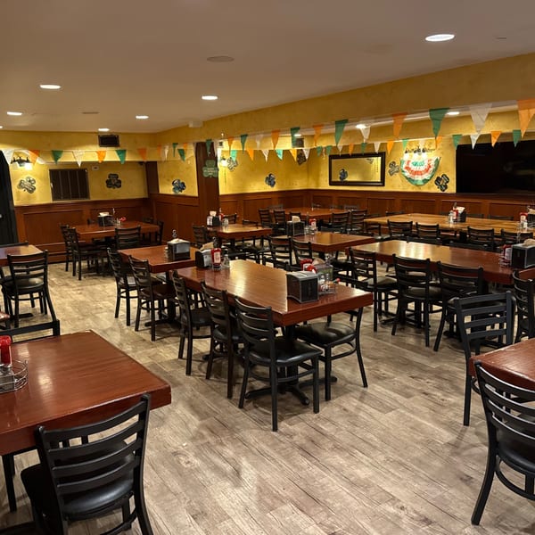 Empty dining room at Bailey's Smokehouse with wooden tables, black chairs, and Irish-themed decorations.