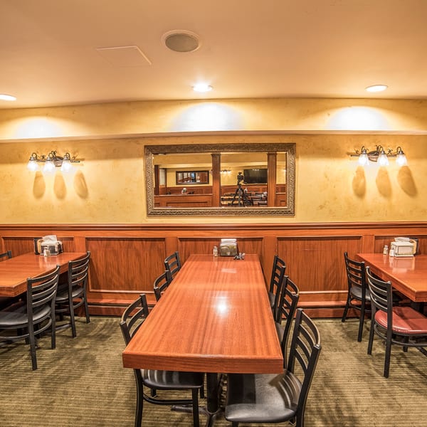 Interior of Bailey's Smokehouse with wooden tables, black chairs, and a large mirror reflecting the dining area.