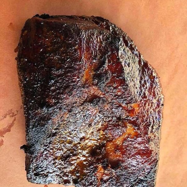 A large, dark, glistening slab of Bailey's Smokehouse BBQ brisket on butcher paper.