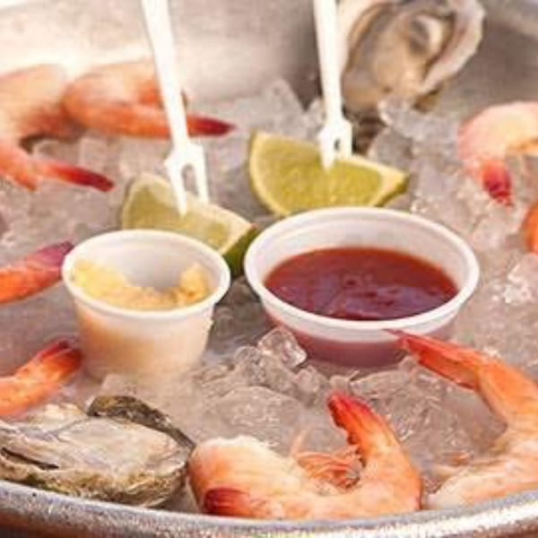 Shrimp, oysters, lime wedges, and sauces on ice, ready to be served at Bailey's Smokehouse.