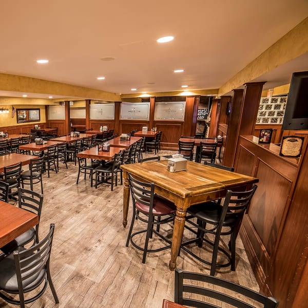 Spacious dining room at Bailey's Smokehouse with numerous wooden tables, black chairs, and warm lighting.