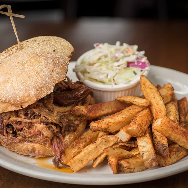 Bailey's Smokehouse pulled pork sandwich with a side of seasoned fries and coleslaw.