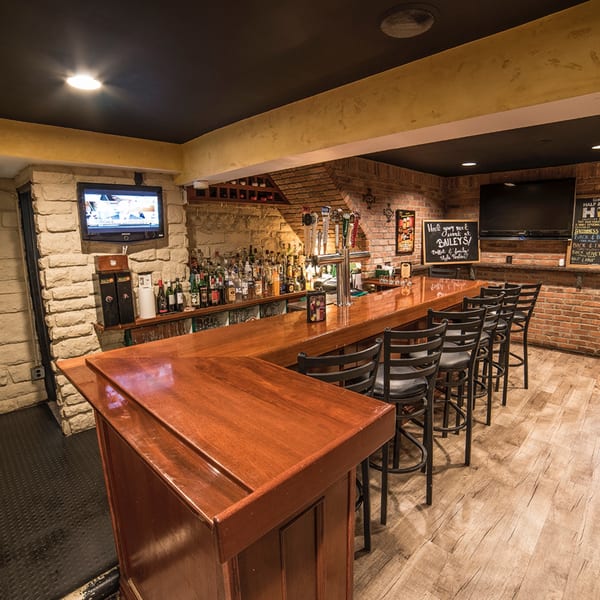 Bailey's Smokehouse bar with a long wooden counter, bar stools, brick walls, and multiple beer taps.