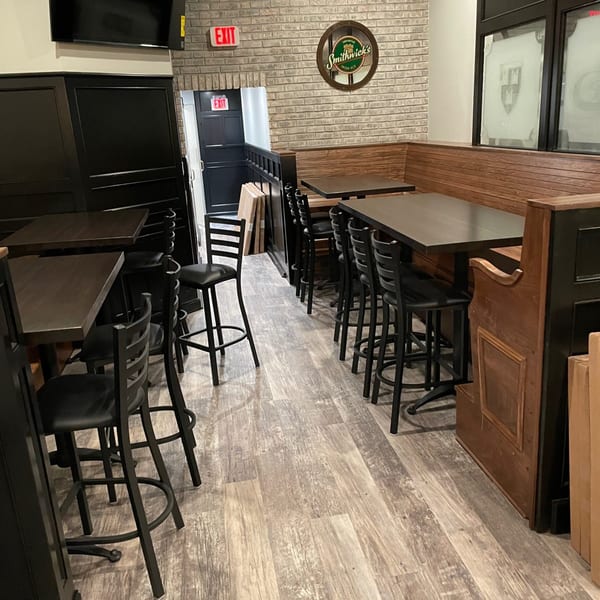 Interior of Bailey's Smokehouse with dark tables, chairs, and booths against a brick wall.